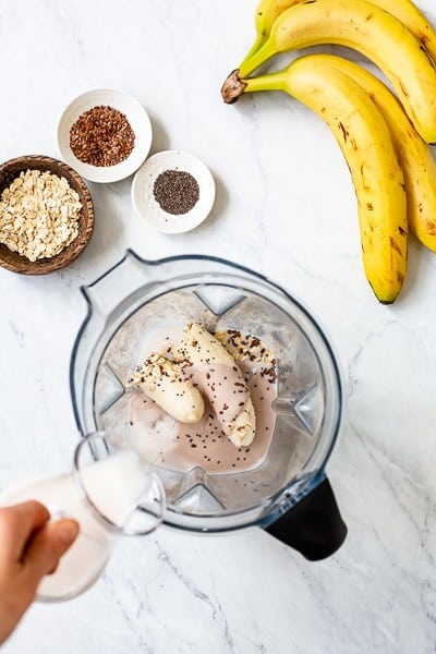 Simple Banana Smoothie with Milk - a woman pouring milk