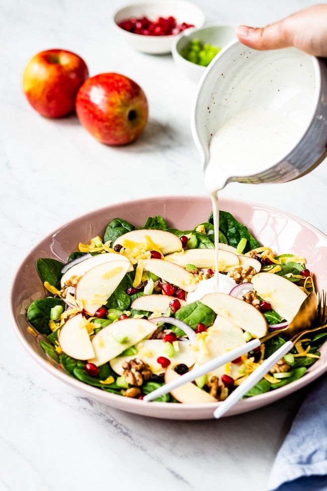 Apple Salad with Yogurt Dressing photographed as a woman is pouring dressing