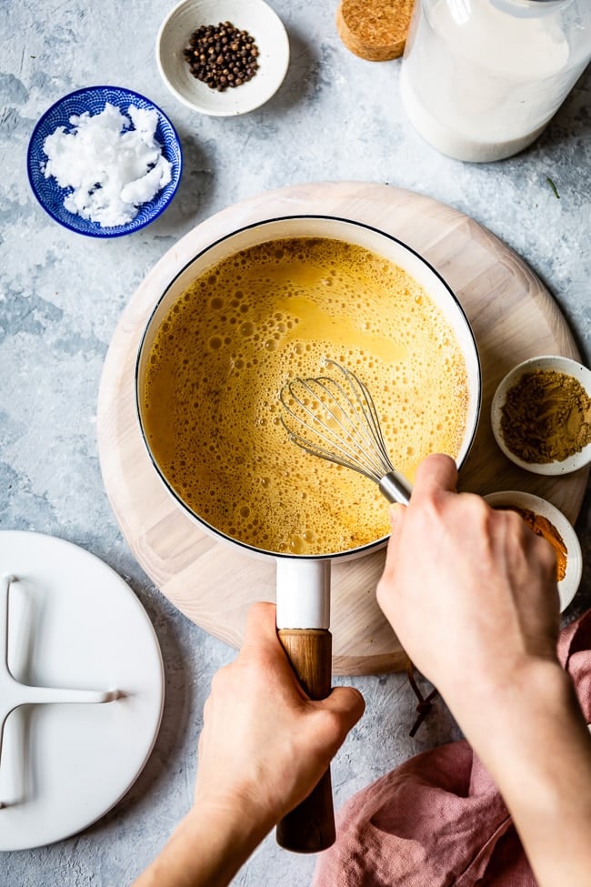 A woman is Whisking turmeric milk