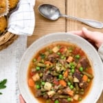 A woman is serving The best vegetable beef soup recipe