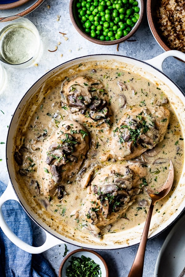 A pot of fricassee chicken recipe is photographed from the top with green peas and bulgur pilaf on the side.