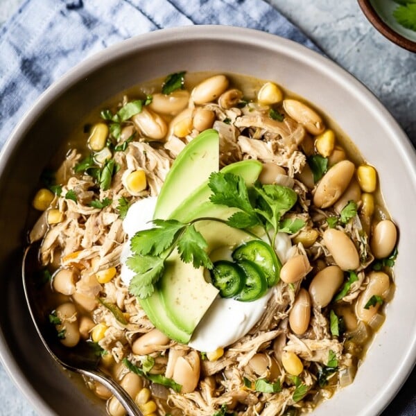 Healthy white chicken chili in a bowl and garnished with chili toppings like avocados and cilantro