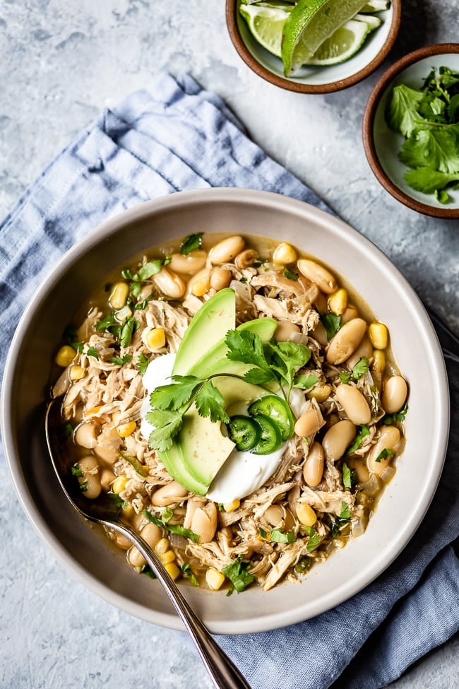 Healthy White Chicken Chili recipe placed in a bowl and garnished with avocado and cilantro.