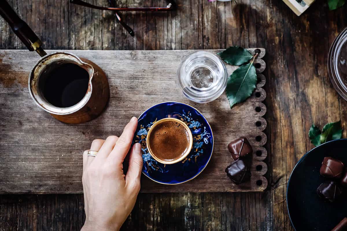Turkish coffee in a blue coffee cup served with chocolate on the side.