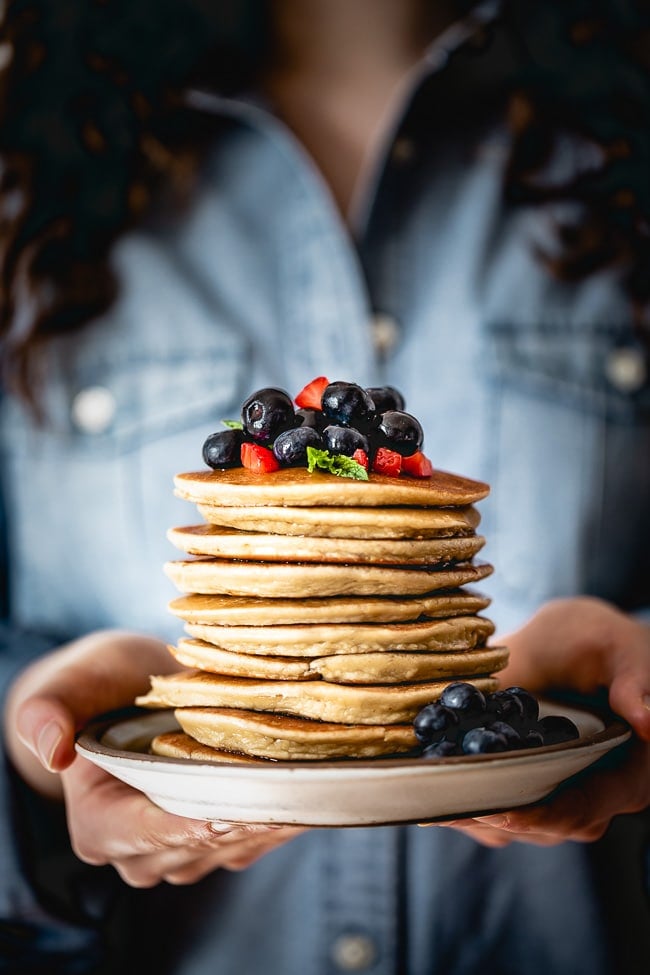 Easy Almond Flour Pancakes topped off with fresh fruit in a woman's hand