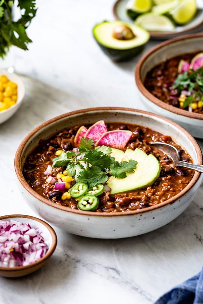 Vegetarian Chili served in a bowl topped off with avocado