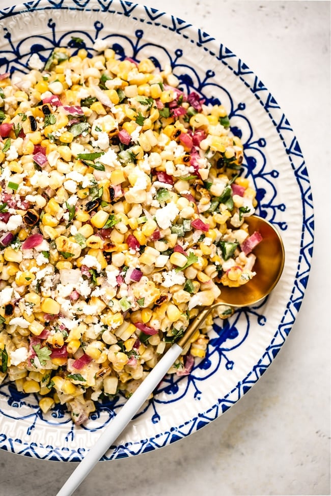 Esquites (or elotes salad) in a plate with a spoon on the side