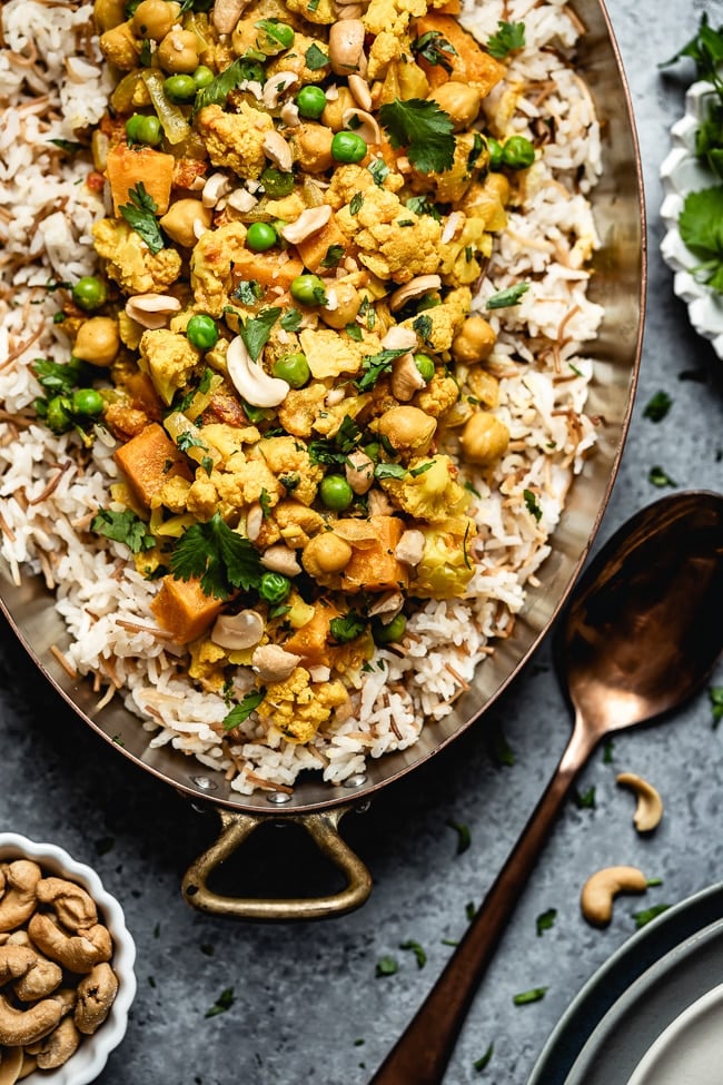 Cauliflower curry with coconut milk and sweet potatoes is placed in a copper pan and photographed from the top view