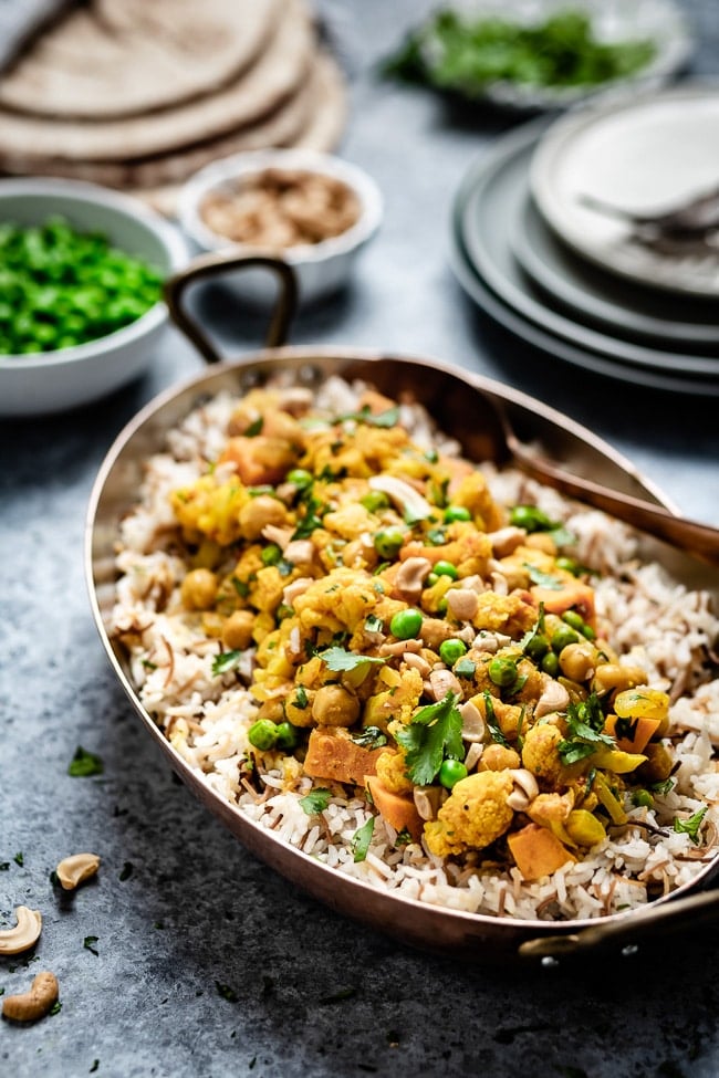 Indian Cauliflower curry placed in an oval tin on top of rice and photographed from the front view.