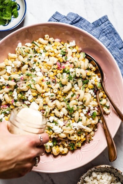 Mexican Street Corn Pasta Salad photographed as it is being drizzled with chipotle lime sauce from the top view