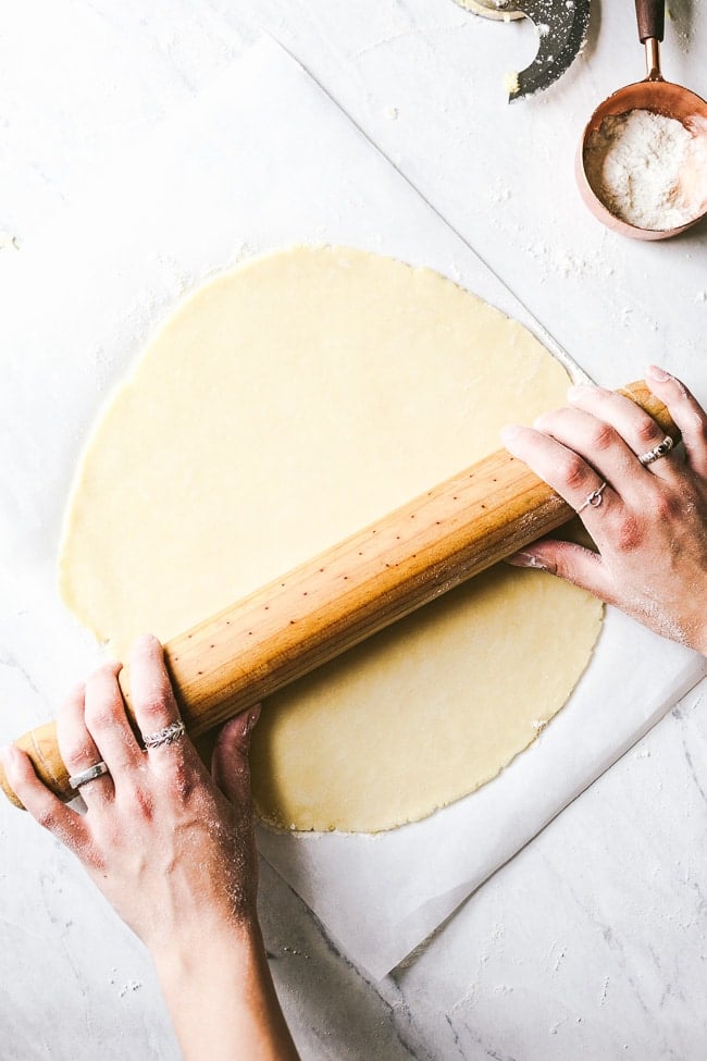 Learn how to make homemade galette dough from scratch - a woman is rolling galette dough