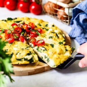 Person taking a slice of the spinach and egg frittata.