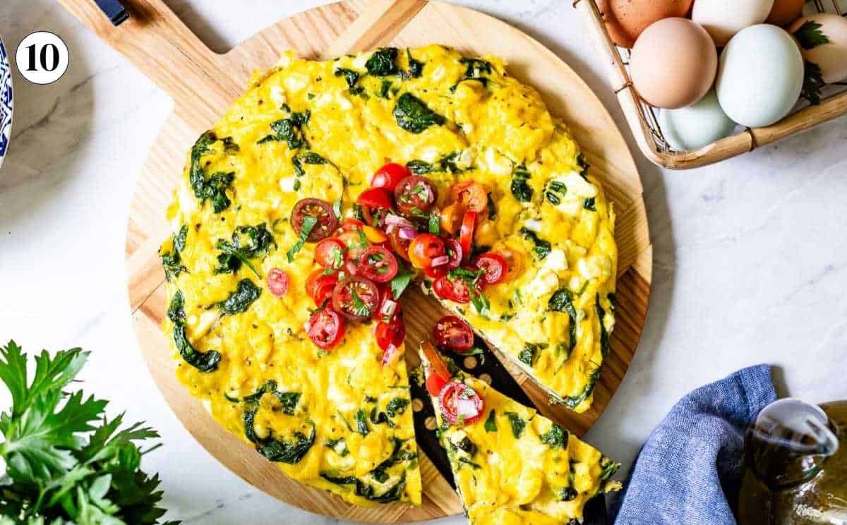 Fresh out of oven spinach and feta cheese frittata on a cutting board from the top view.