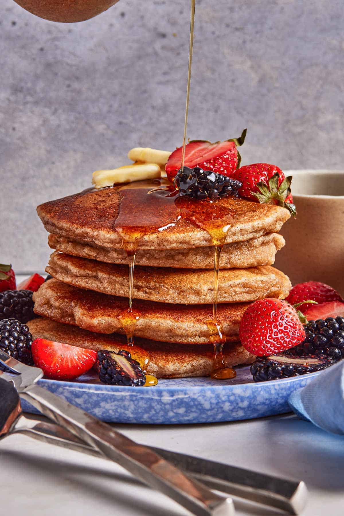 Almond flour pancakes stacked and being drizzled with maple syrup.