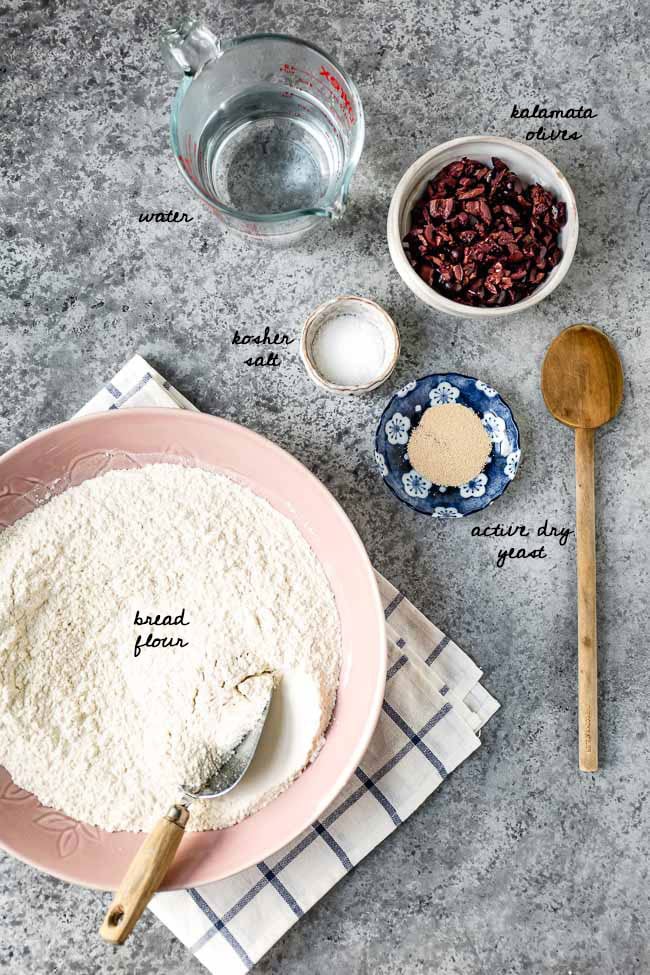 What is olive loaf made of: Ingredients for rustic olive bread recipe are laid out and photographed from the top view.