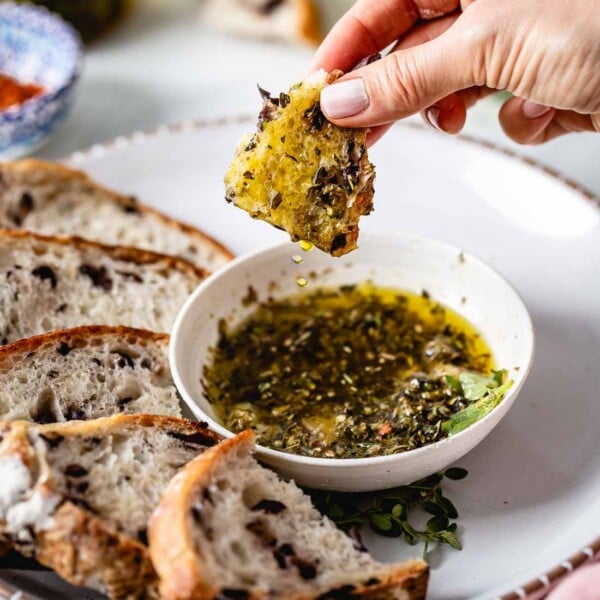 Person dipping bread in olive oil dip
