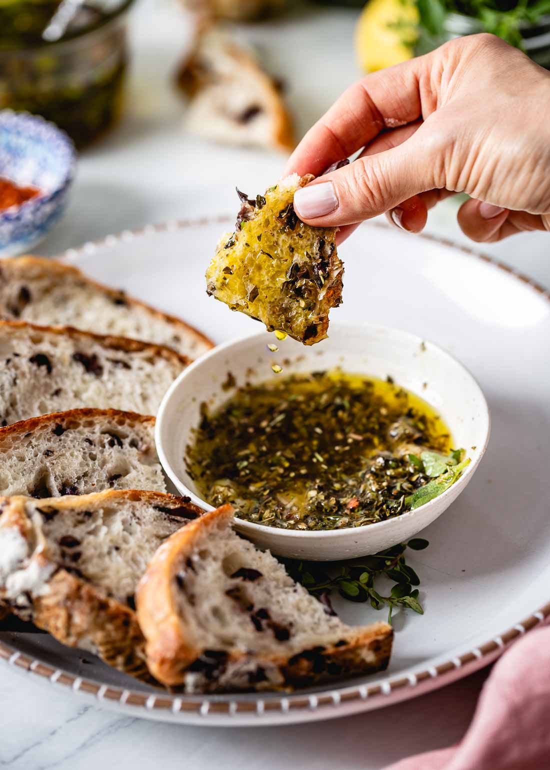 A woman is photographed right after she dipped a piece of bread in to the Olive oil bread dip 