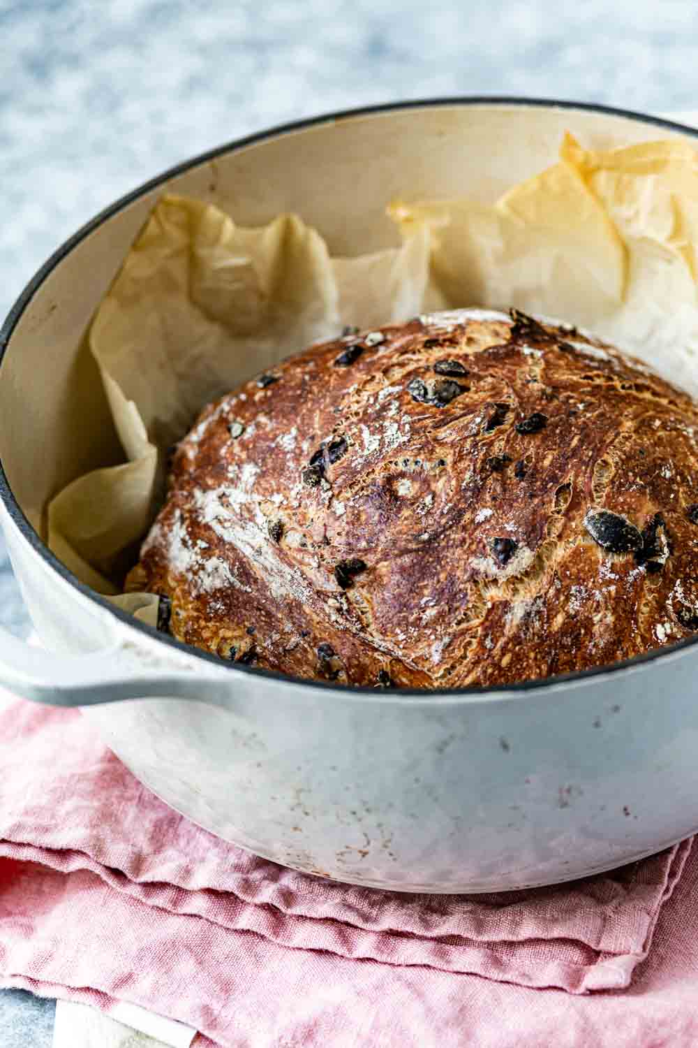 Dutch oven no knead olive loaf recipe is photographed right after it came out of the oven