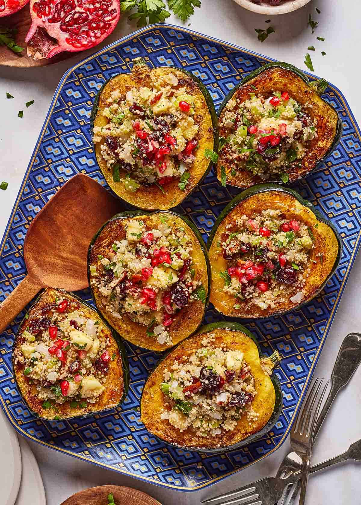 Quinoa stuffed acorn squash halves garnished with pomegranate arils.