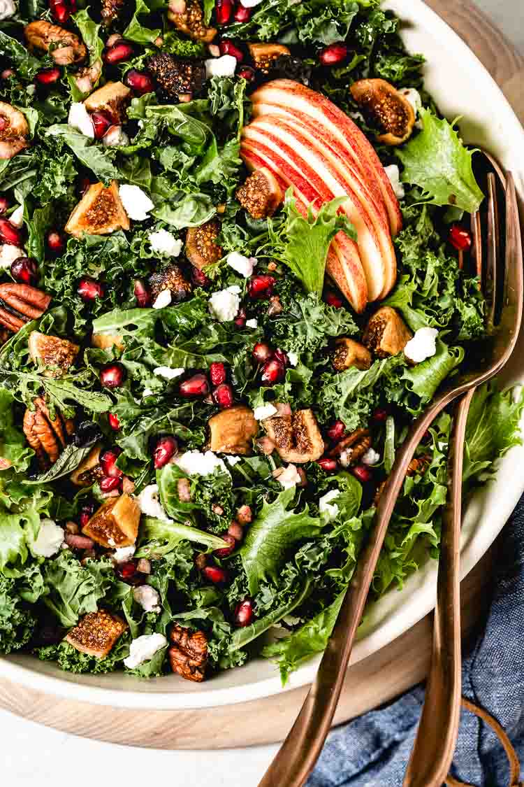 Harvest Kale Salad packed with apples, figs, and goat cheese photographed from the top view.