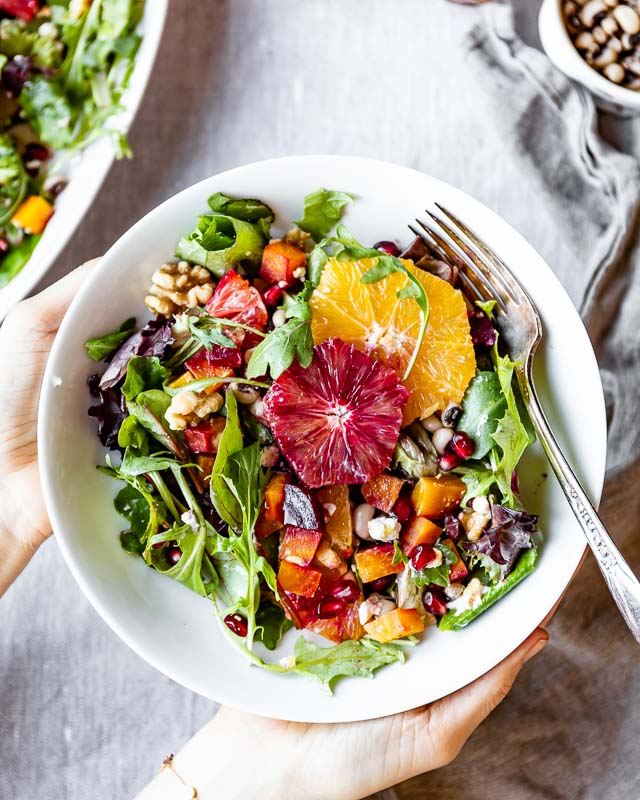 Salad with oranges in a bowl held by a woman