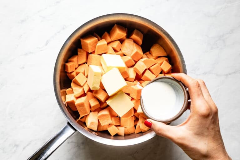 Person pouring in heavy cream into saucepan.