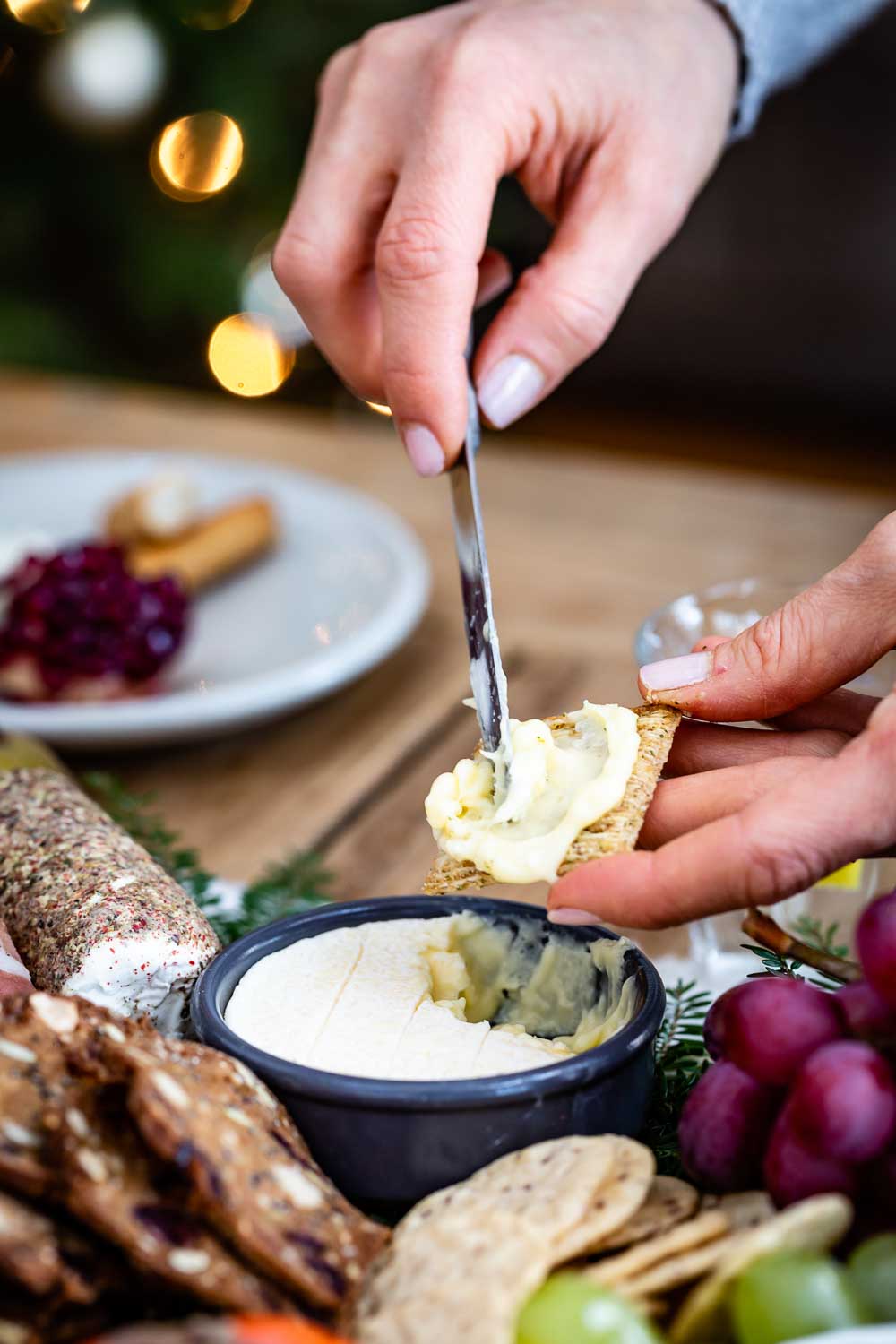 A woman is spreading goat cheese dip on a cracker