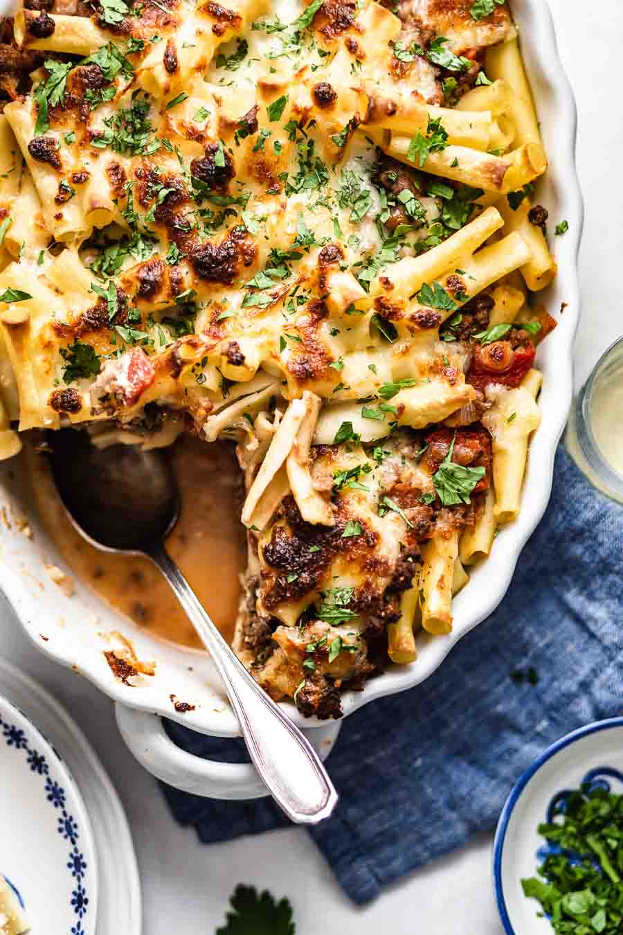 a casserole dish of Baked Ziti with Meat Sauce with a spoon on the corner