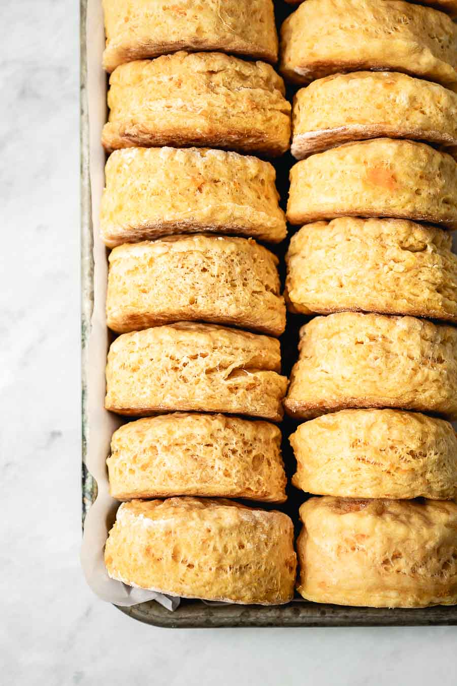Buttery and flaky sweet potato biscuits are placed on a tray and photographed from the top view.