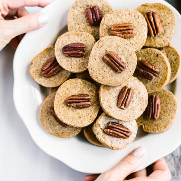 Pecan Shortbread Cookies are served by a woman photographed from the top view.