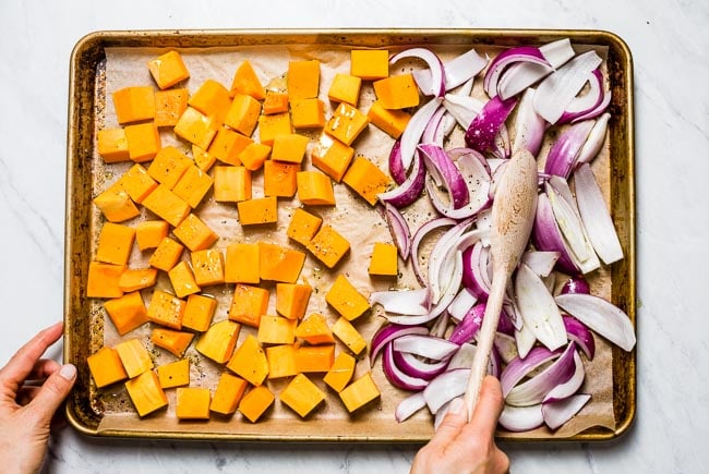 a woman is preparing vegetables for roasting