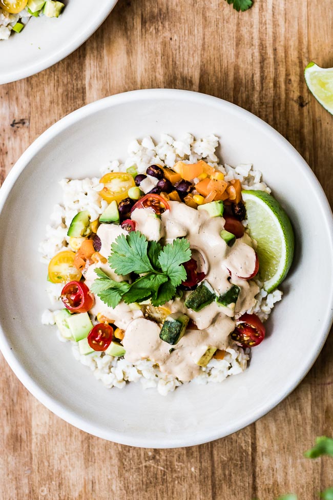 Vegan Burrito Bowl recipe topped off with vegan creamy chipotle sauce and cilantro.