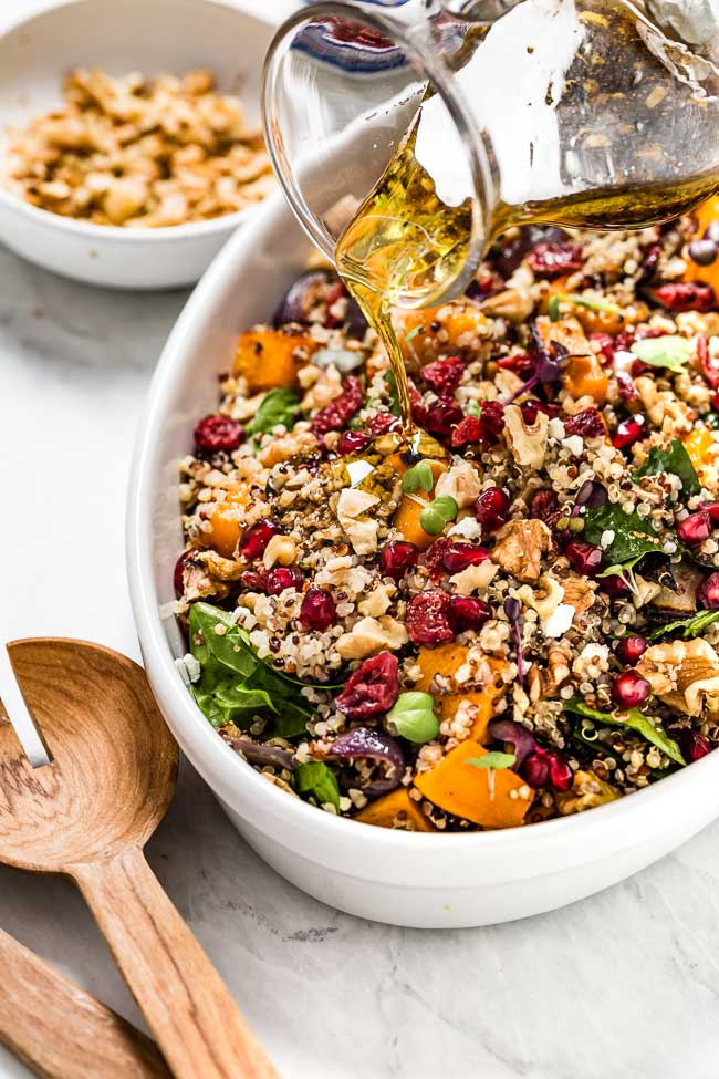 Roasted Butternut Squash and Cranberry Salad is being drizzled with balsamic vinaigrette.