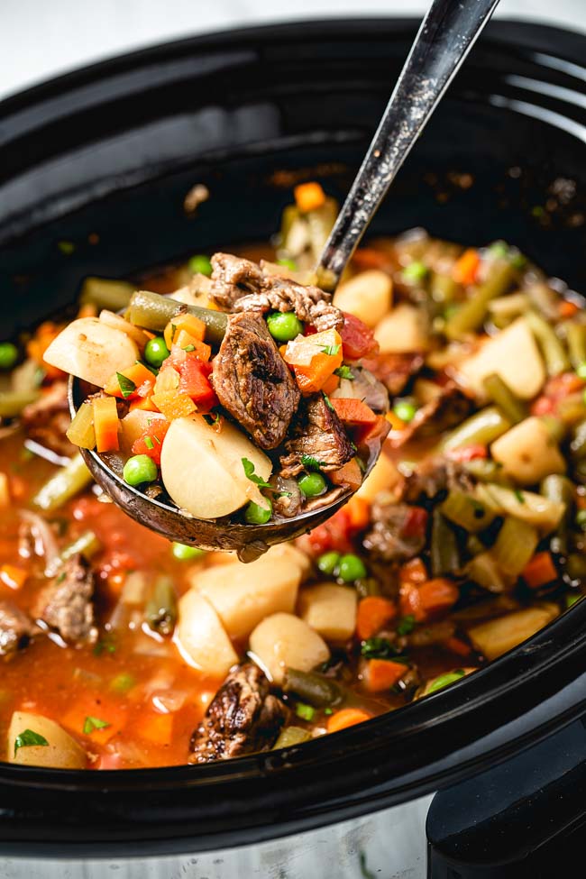 A ladle of soup is photographed from the front from a close up view.