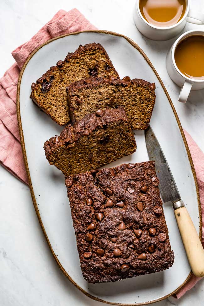 A few slices of Almond Flour Banana Bread served on a plate with two cups of coffee on the side photographed from the top view