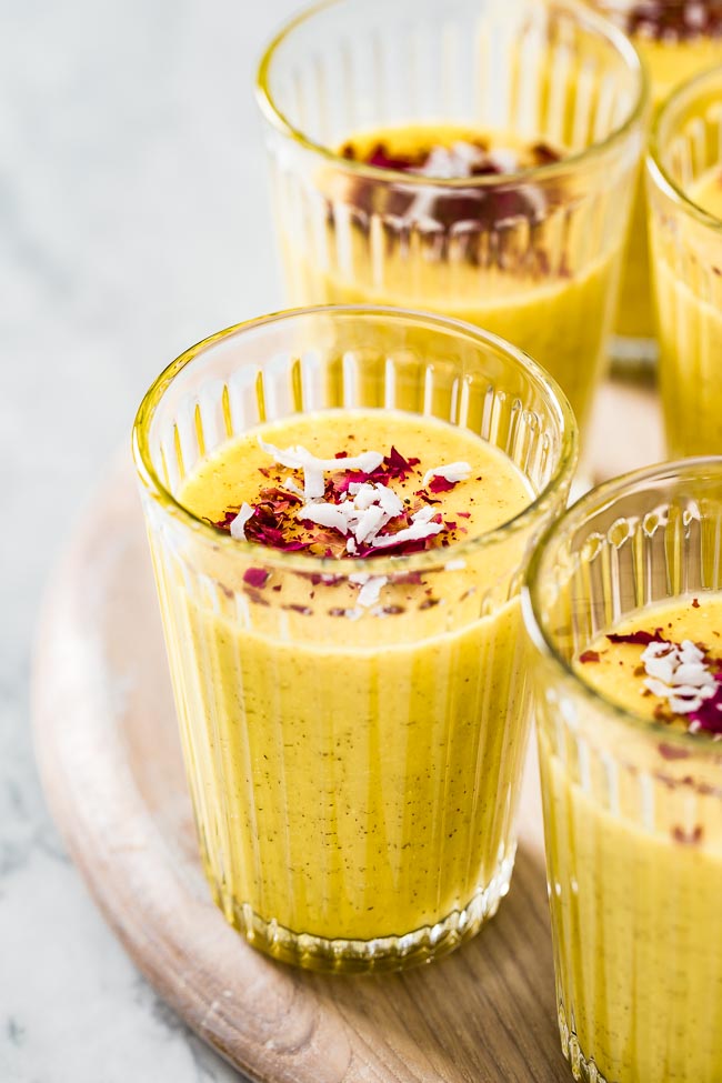 A few glasses of mango turmeric smoothie photographed from the front view.