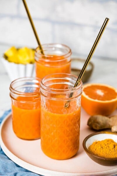 three glasses of turmeric ginger smoothie are photographed from the front view