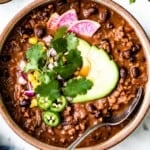 Vegan Chili in a bowl garnished with avocados and cilantro