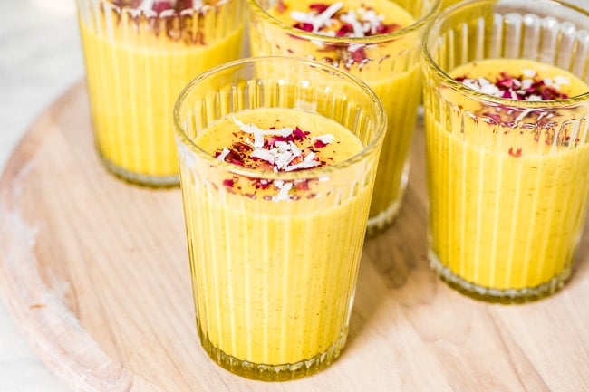 A few glasses of turmeric mango smoothie photographed from the front view.