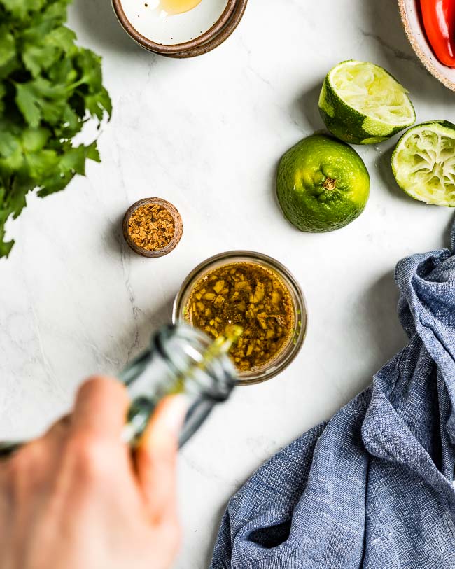 A woman is photographed from the top view as she is making Chile Lime Vinaigrette