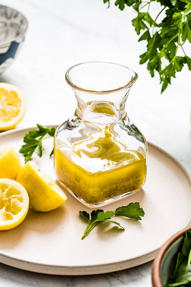 A bottle of homemade lemon vinaigrette dressing recipe is photographed from the front