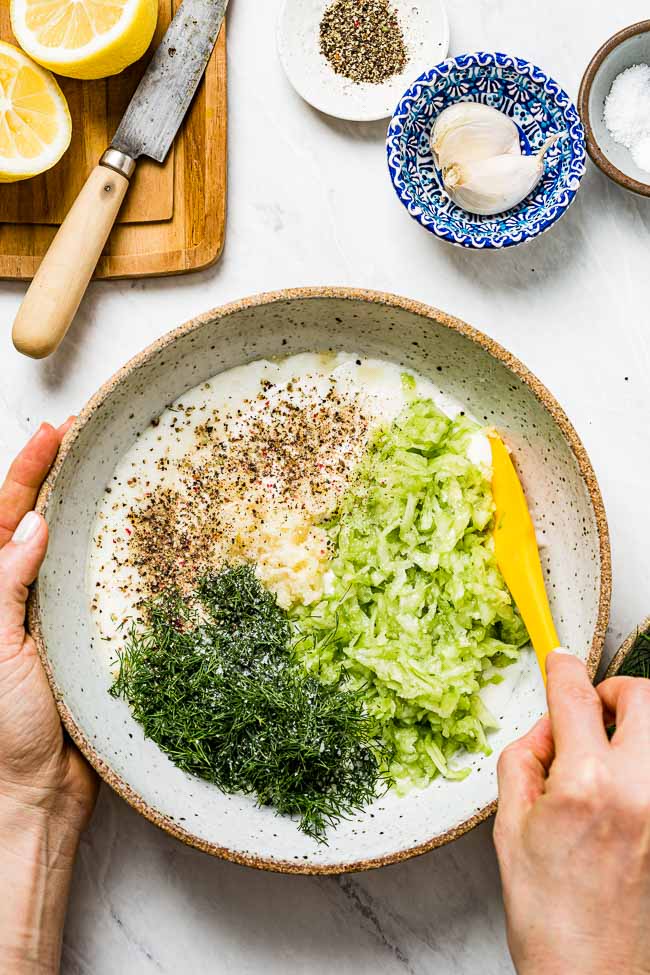 All ingredients are placed in a large bowl as a woman is getting ready to mix it