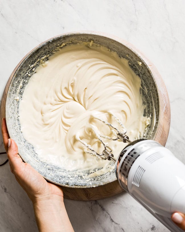 A woman is mixing maple icing with a mixer