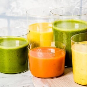 A few glasses of turmeric smoothies are photographed from the front view.