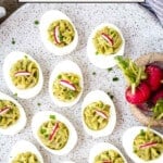 Deviled eggs on a plate garnished with radishes and chives with text on the image