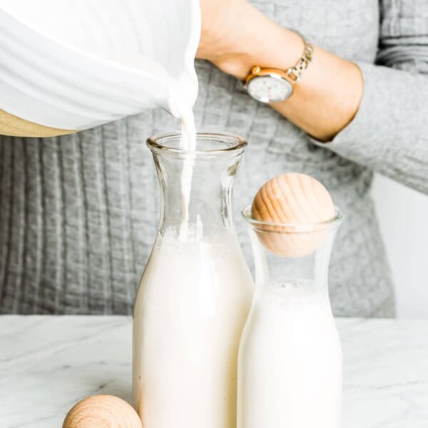 Almond milk is being poured into a jar by a woman