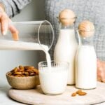 person pouring homemade almond milk in a glass