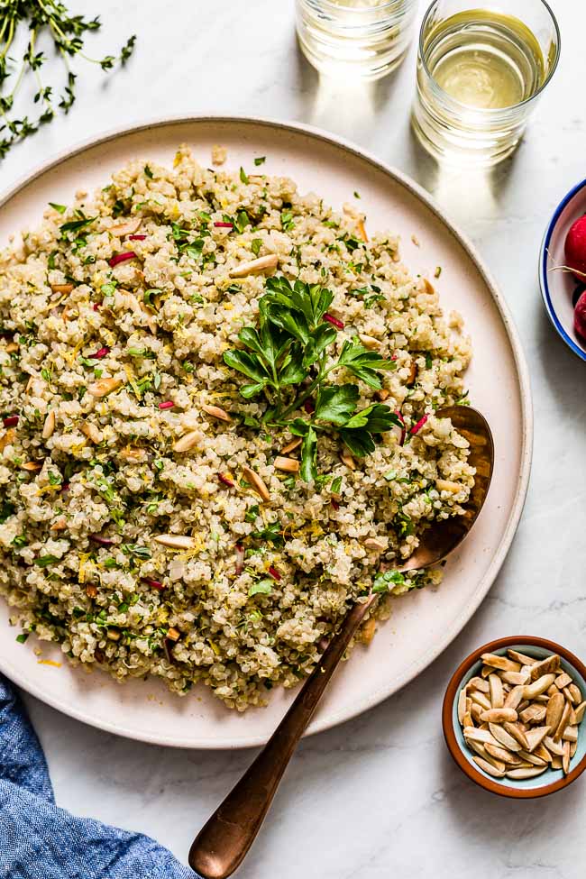 Herbed lemon quinoa served in a large plate with fresh parsley, sliced almonds, and lemon.