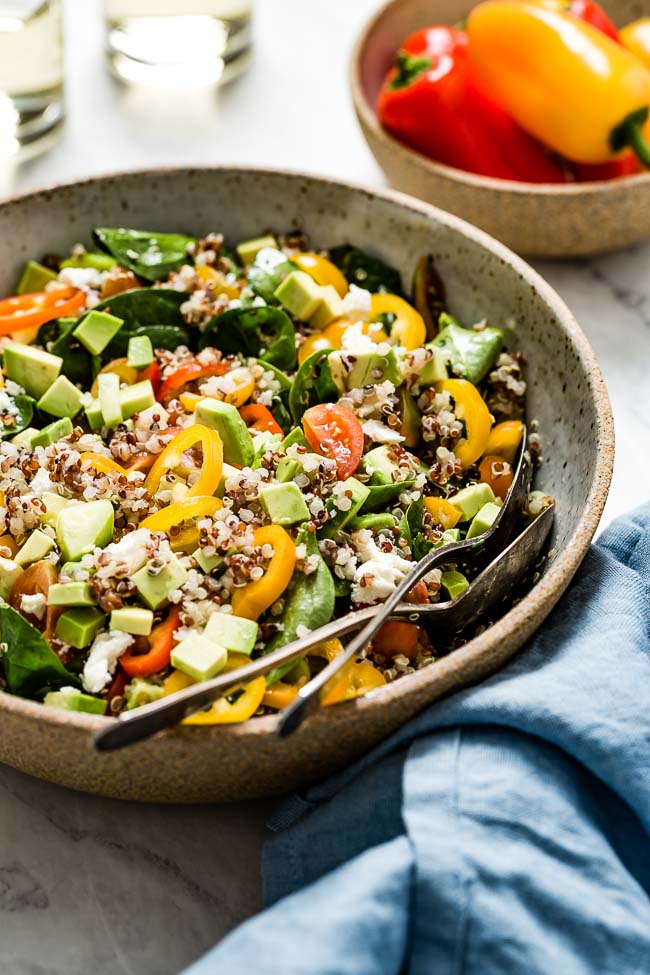 A bowl of quinoa salad avocado tomato cucumber photographed from the front view