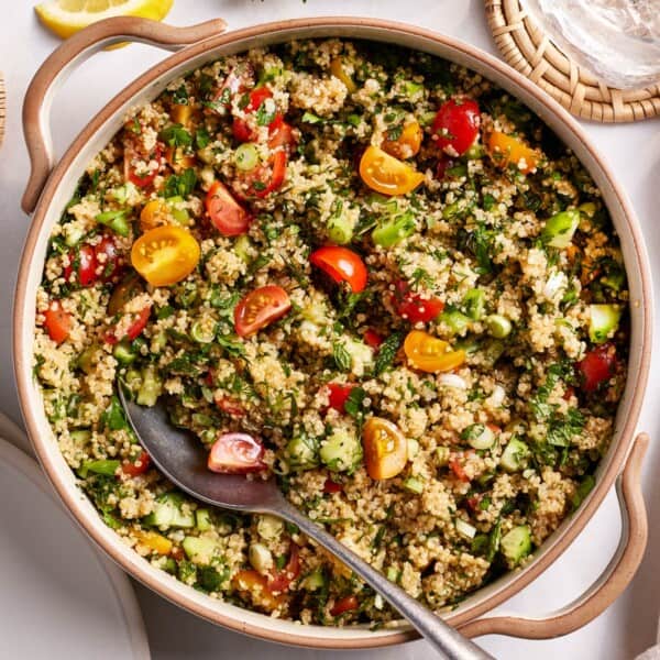 Quinoa tabbouleh in a salad bowl with a spoon on the side.